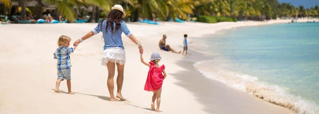 Beautiful mother, son and daughter walking on the beach of the Indian ocean